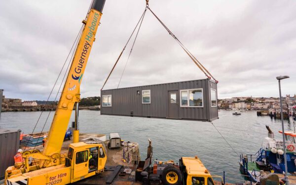 shipping container signal station hoisted by guernsey horbours crane