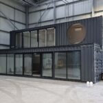 3 shipping containers glass sides under contruction grey paint